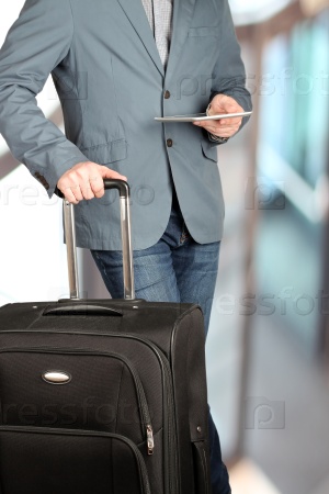 picture of a close up man using a digital tablet with baggage behind