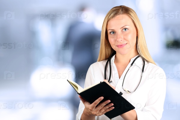 Image of woman doctor looking at camera and writing in your pad
