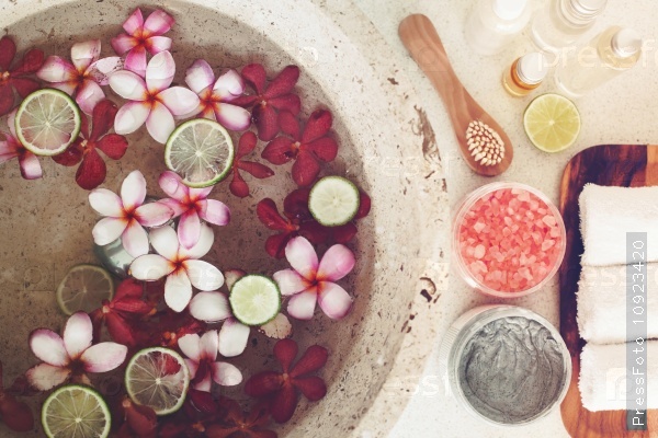 Foot bath in bowl with lime and tropical flowers, spa pedicure treatment, top view, stock photo