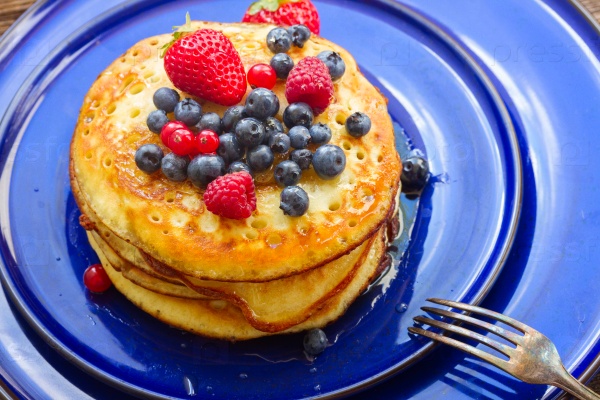 Baked Pancakes with fresh berries on blue plate close up , stock photo