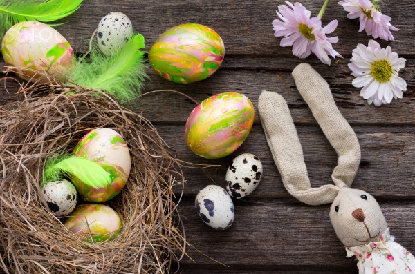 Easter background with colored eggs in nest and home made decoration on rustic wooden board, stock photo