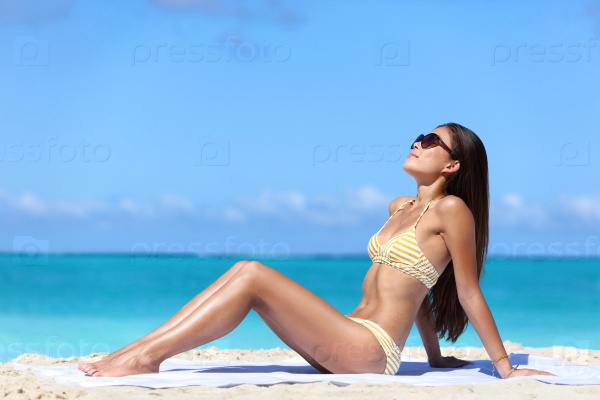 Beach sunglasses woman sun tanning in sexy bikini. Full body girl lying down getting a suntan on skin wearing eyewear. Skincare solar uv rays protection concept.