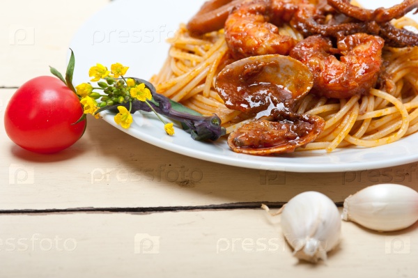 Italian seafood spaghetti pasta on red tomato sauce over white rustic wood table, stock photo