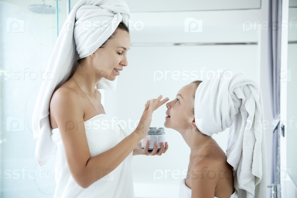 Mother and tween daughter make a clay facial mask, family scin care in the bathroom, stock photo
