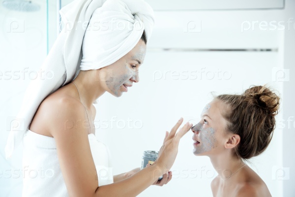 Mother and tween daughter make a clay facial mask, family skin care in the bathroom