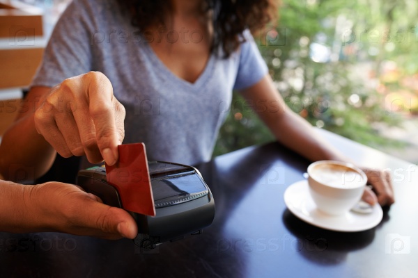 Close-up image of woman paying with credit card in cafe