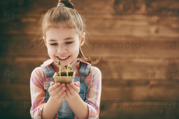 Cute little child girl planting seedlings. Fun little gardener. Spring concept, nature and care.