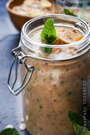 Fruit smoothie in a glass jars with mint on the blue stone table