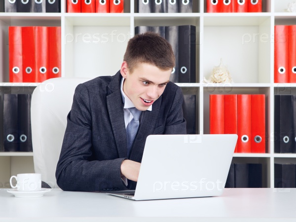confident young businessman looking at laptop in office