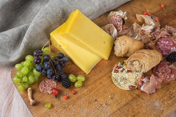 Fresh grapes, cheese bacon berries and salami on wooden table, stock photo