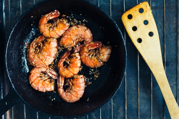 Wild red Argentine shrimp fried in the pan in butter with garlic and sesame seeds, top view, stock photo