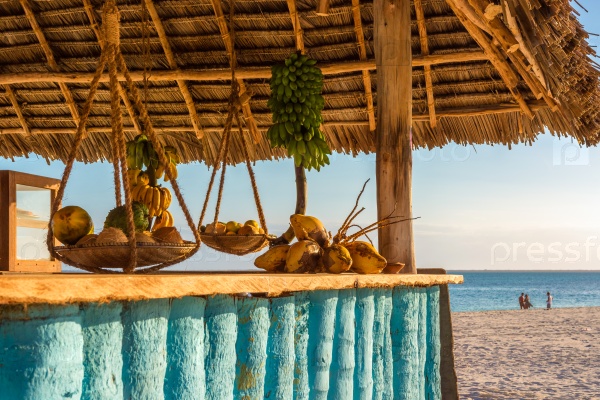 In the picture beach bar in Nungwi ( Zanzibar ) at sunset , with exposed coconut , banana and tropical fruit .This bar is made with cane bamboo,wooden and straw rope.