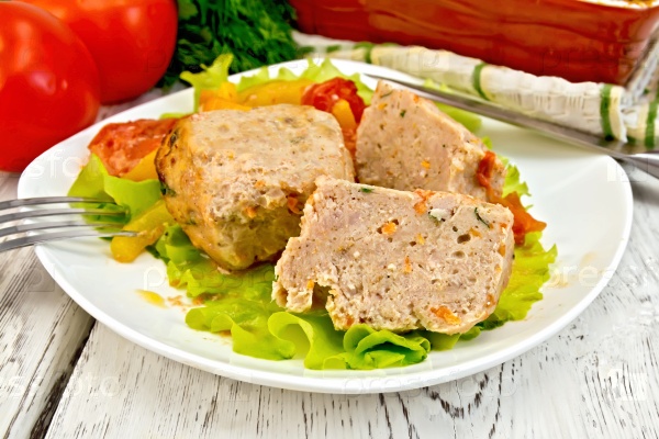 Cutlet of turkey meat with lettuce, tomato and yellow pepper in a dish, parsley, a towel and a fork on the background of wooden boards, stock photo