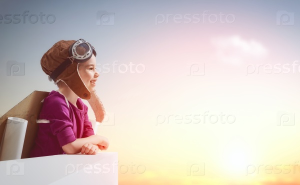 Little child girl plays astronaut. Child on the background of sunset sky. Child in an astronaut costume plays and dreams of becoming a spaceman.