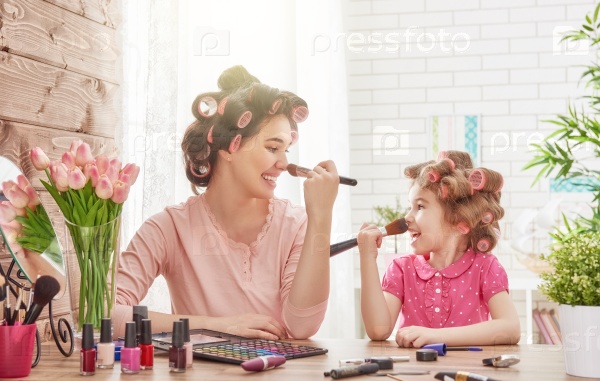 Happy loving family. Mother and daughter are doing hair, manicures, doing your makeup and having fun. Mother and daughter sitting at dressing table at house.