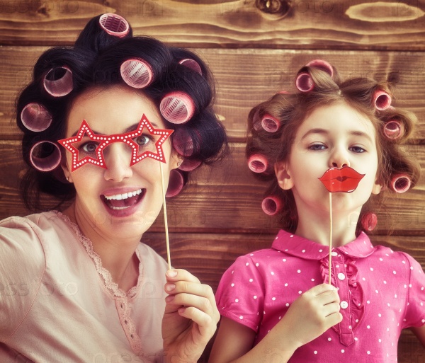 Funny family! Mother and her child daughter girl with a paper accessories. Beauty funny girl holding paper lips on stick. Beautiful young woman holding paper glasses on stick.