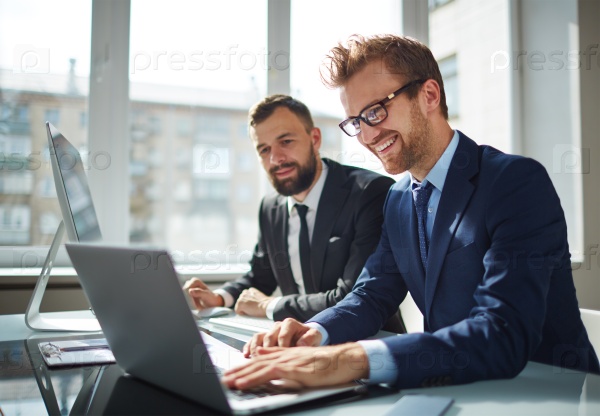 Two business partners working with laptop together, stock photo