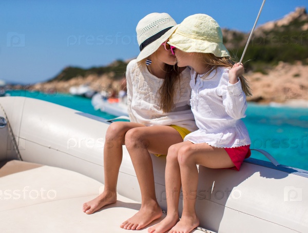 Little cute girls enjoying sailing on boat in the open sea