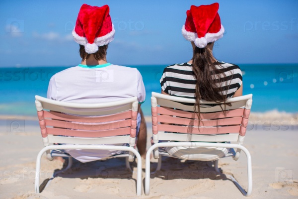 Back view of couple in Santa hats enjoy beach vacation