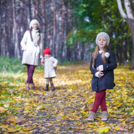 Little cute girls and young mother in autumn park have fun