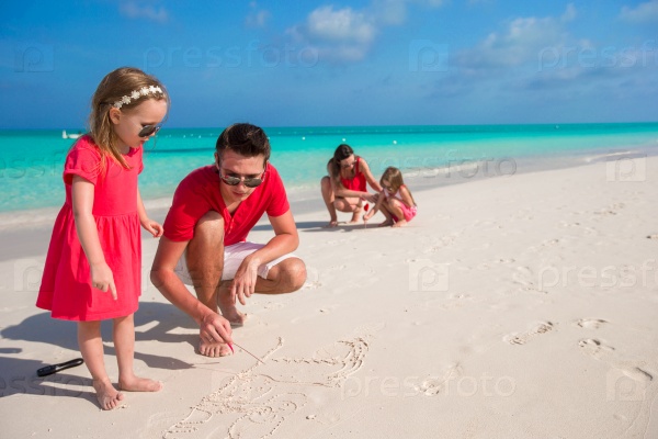 Young family painting on the sand during vacation