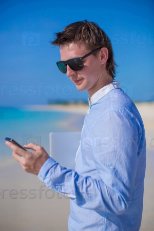 Businessman with phone in hand on a tropical beach