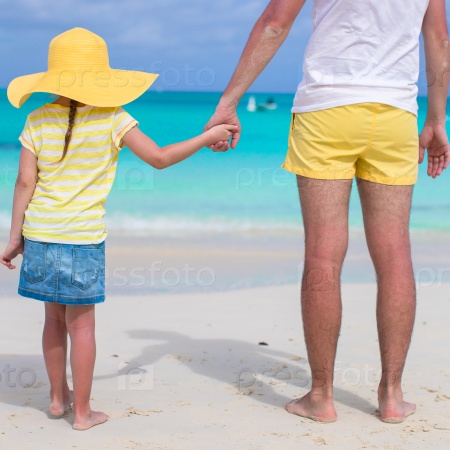 Close up of little girl holding her father hand on the beach, stock photo