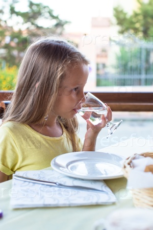 Adorable little girl having breakfast and drinking water