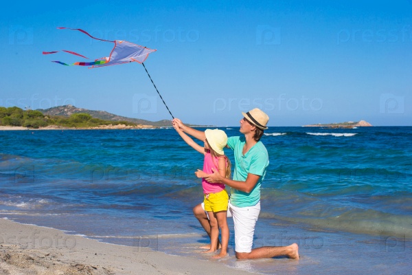 Happy dad and cute little daughter flying kite together