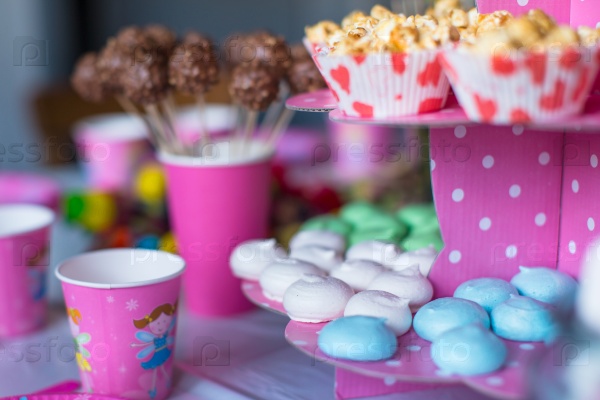 Sweet colored meringues, popcorn, custard cakes and cake pops on table