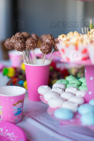 Sweet colored meringues, popcorn, custard cakes and cake pops on table