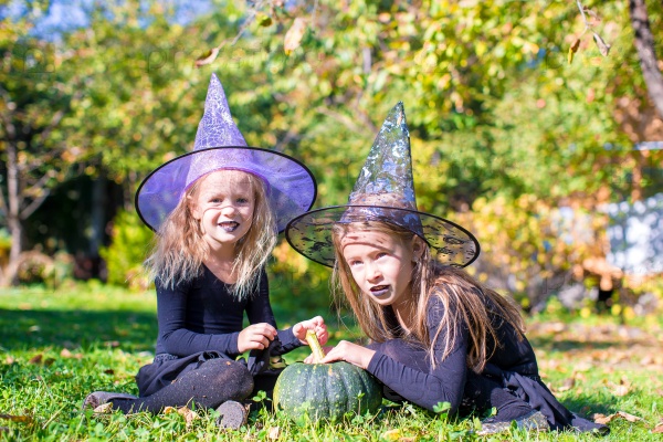 Adorable little girls in witch costume casting a spell on Halloween