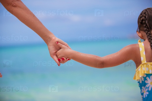 Closup hands of mother and daughter walking on the beach