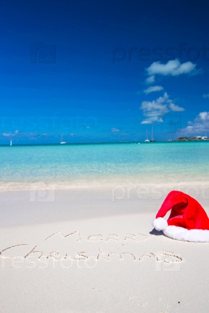 Merry Christmas written on tropical beach white sand with xmas hat