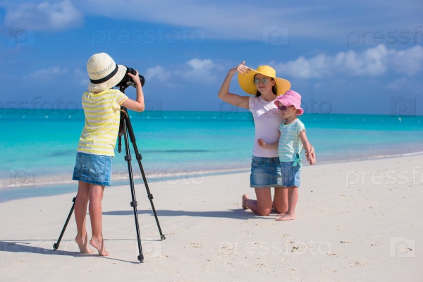 Little girl photographing her mother and sister on the beach, stock photo