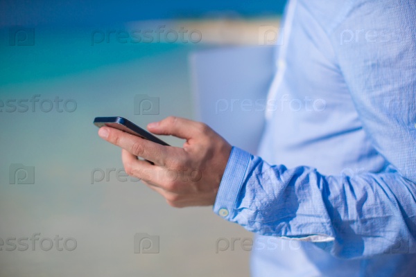 Close up telephone in male hand at tropical beach