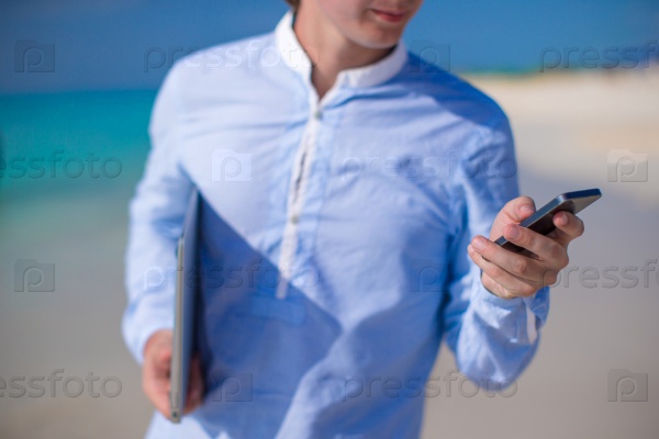 Close up telephone in male hand at tropical beach