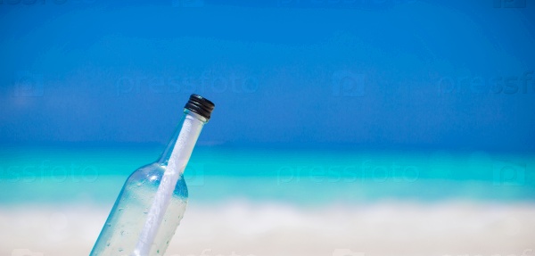 Bottle with a message buried in the white sand, stock photo