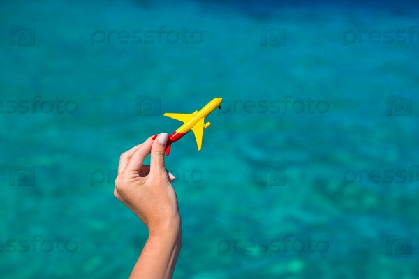 Small homemade plane in female hand on background of the sea