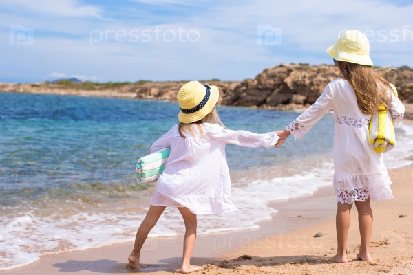 Adorable cute girls have fun on white beach during vacation