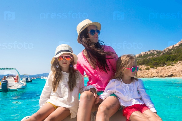 Young mother with her adorable daughters resting on a big boat