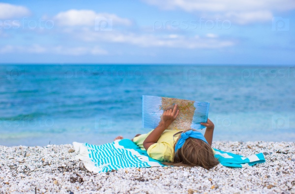 Adorable little girl with big map on tropical beach vacation, stock photo