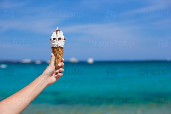 Closeup of tasty ice cream in female hand background the turquoise sea