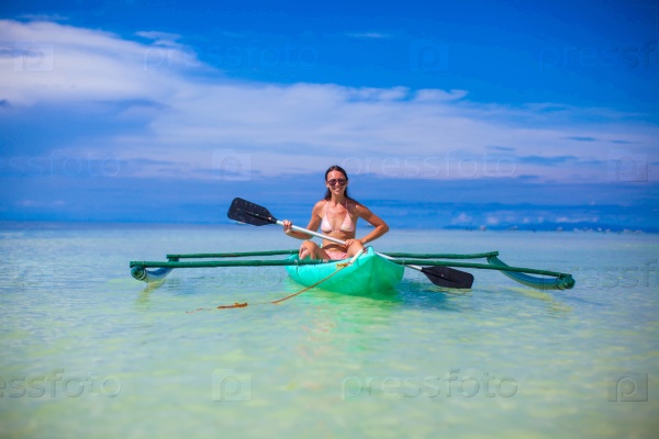 Young woman kayaking alone in the clear blue sea, stock photo
