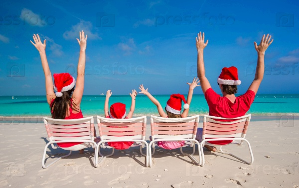 Happy family of four in Christmas Hats during tropical vacation