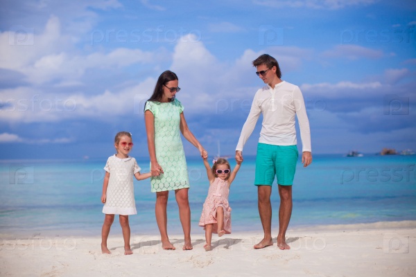 Family of four walking by the sea and enjoy beach vacation