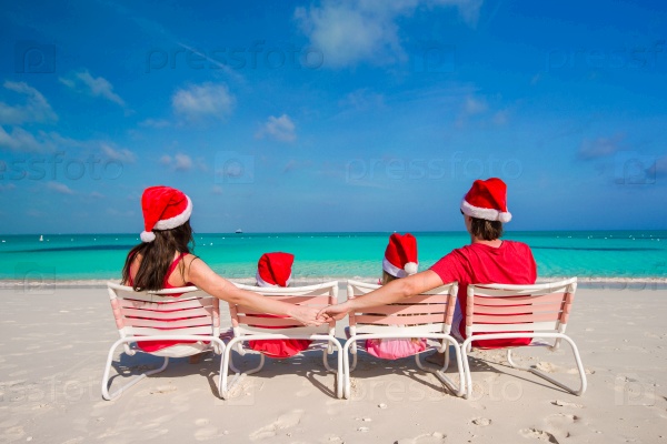 Happy family of four in Christmas Hats during tropical vacation