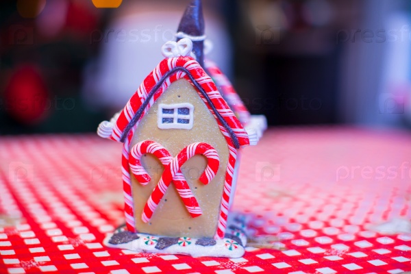 Gingerbread fairy house decorated with colorful candies on a background of bright Christmas tree with garland, stock photo