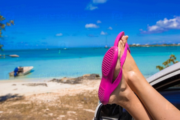 Female feet from the window of a car on a background of tropical beach, stock photo