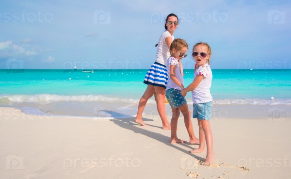 Little adorable girls having fun with happy mom during beach\
vacation